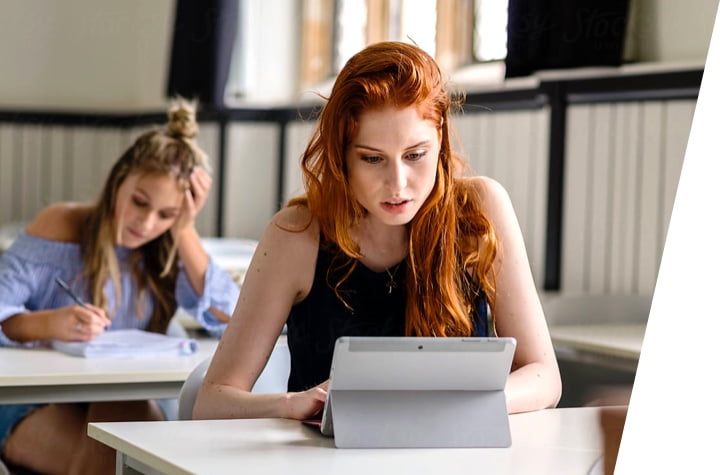 A photo of a red haired girl and a blonde haired girl working on their iPads