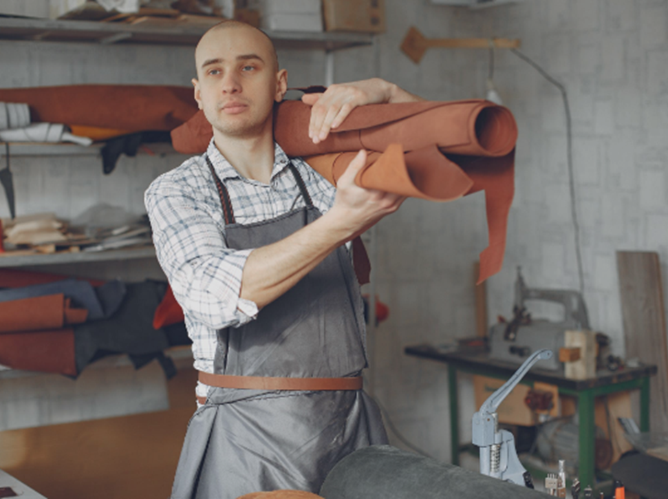 Person working in a workshop carrying a roll of fabric on their shoulder